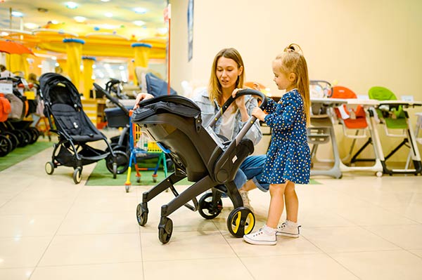 A mother is selecting a stroller for her daughter.